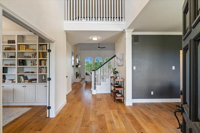 19215 White Horse Cv, Spicewood, TX 78669 - entrance foyer with baseboards, light wood-style flooring, stairs, ornamental molding, and ornate columns