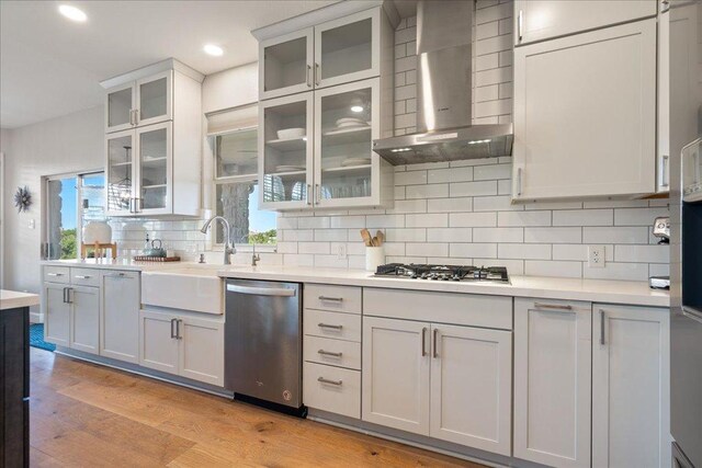 19215 White Horse Cv, Spicewood, TX 78669 - kitchen with stainless steel appliances, wall chimney range hood, a sink, light countertops, and decorative backsplash