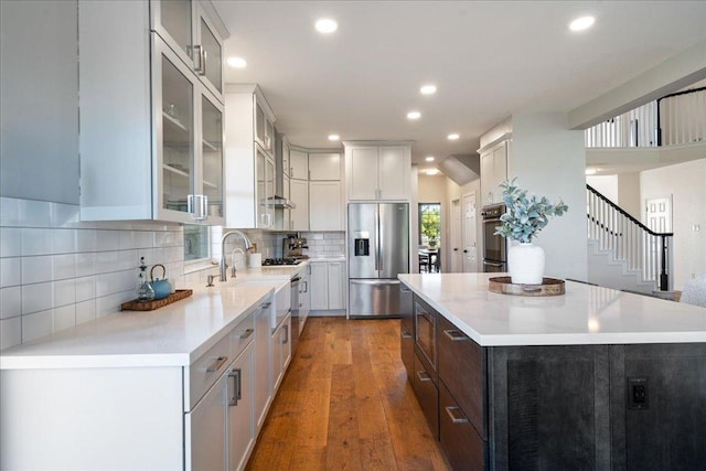 kitchen featuring stainless steel fridge with ice dispenser, a kitchen island, light countertops, glass insert cabinets, and recessed lighting