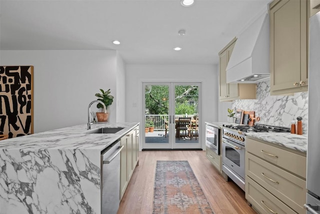 2004 Raleigh Ave, Austin, TX 78703 - kitchen featuring premium range hood, appliances with stainless steel finishes, tasteful backsplash, light stone counters, and light wood-style floors