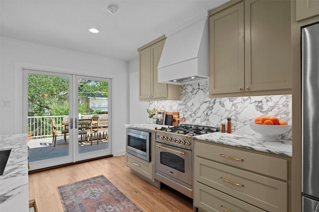 2004 Raleigh Ave, Austin, TX 78703 - kitchen featuring appliances with stainless steel finishes, custom range hood, decorative backsplash, light stone counters, and light wood-style floors
