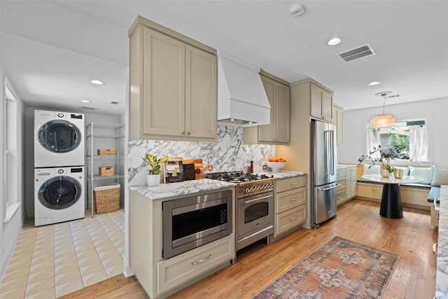 2004 Raleigh Ave, Austin, TX 78703 - kitchen with stainless steel appliances, stacked washer / dryer, premium range hood, tasteful backsplash, and hanging light fixtures