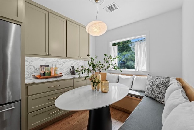 2004 Raleigh Ave, Austin, TX 78703 - kitchen with stainless steel refrigerator, dark wood-type flooring, light stone counters, gray cabinets, and hanging light fixtures