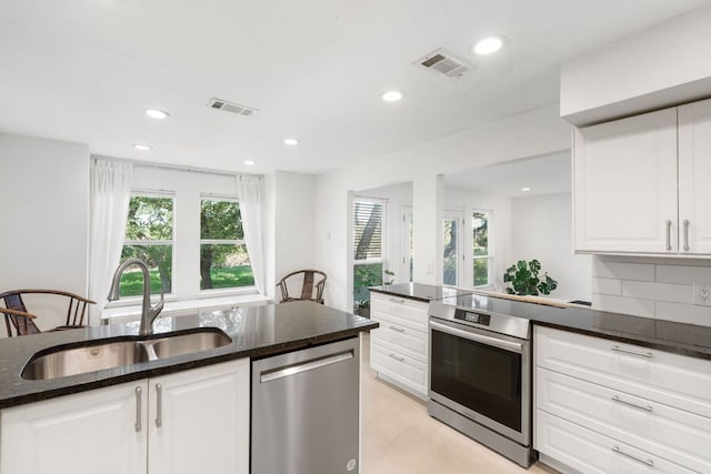 13212 Running Doe Ln, Cedar Park, TX 78613 - kitchen with stainless steel appliances, a sink, dark stone counters, white cabinetry, and recessed lighting