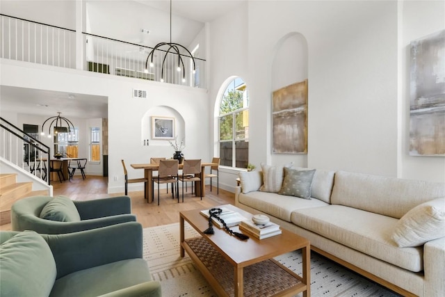 living room featuring a chandelier, light wood finished floors, plenty of natural light, and stairway