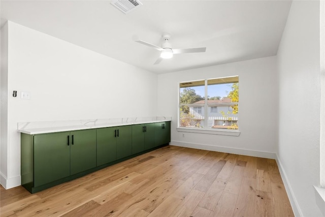 spare room featuring visible vents, light wood-type flooring, baseboards, and a ceiling fan