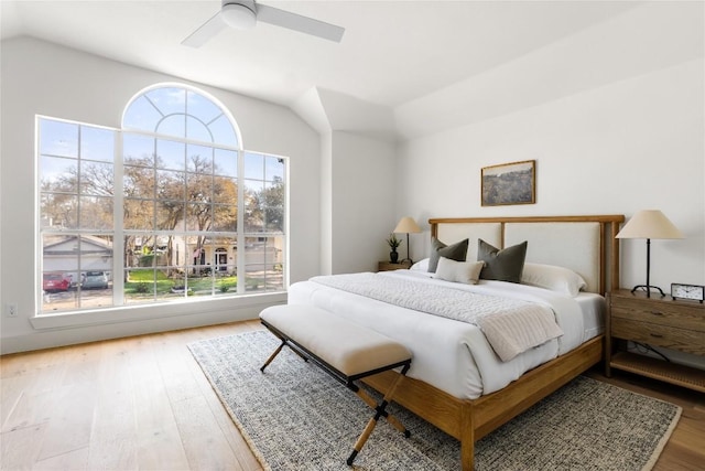 bedroom with wood finished floors, multiple windows, and lofted ceiling
