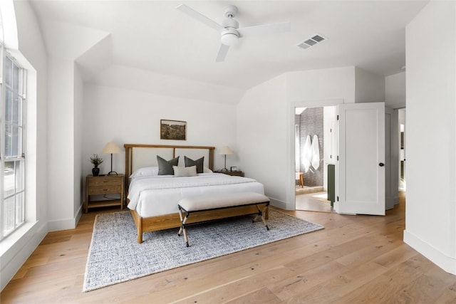 bedroom featuring light wood finished floors, visible vents, baseboards, and lofted ceiling