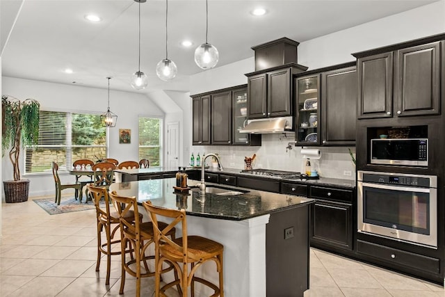 174 Challis Ct, Austin, TX 78737 - kitchen featuring appliances with stainless steel finishes, a sink, light tile patterned floors, decorative backsplash, and a breakfast bar
