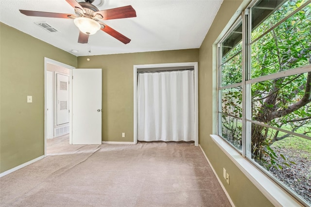unfurnished bedroom featuring baseboards, a ceiling fan, carpet flooring, and visible vents