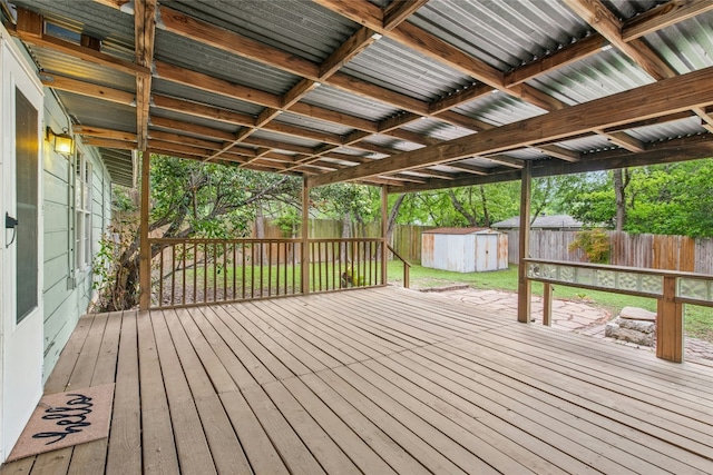 deck featuring a fenced backyard, a storage unit, and an outbuilding