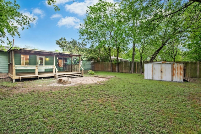 view of yard featuring a fenced backyard, a wooden deck, a patio area, an outdoor structure, and a shed