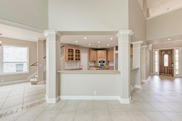 8105 Endeavor Cir, Austin, TX 78726 - kitchen with stainless steel microwave, decorative columns, a towering ceiling, light tile patterned floors, and light countertops