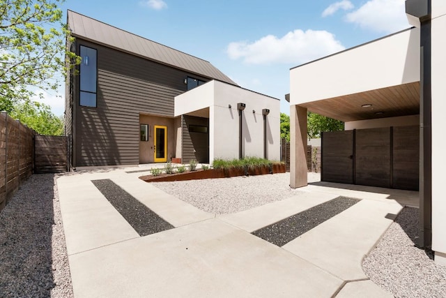 view of front of house with fence, a patio area, and metal roof