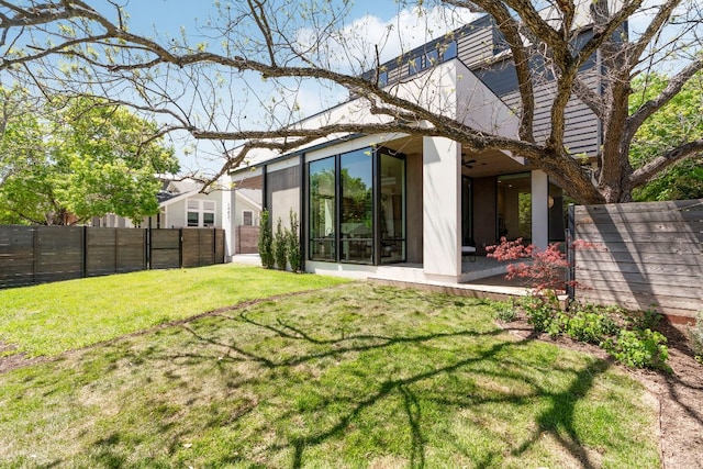 back of house featuring stucco siding, fence, and a yard