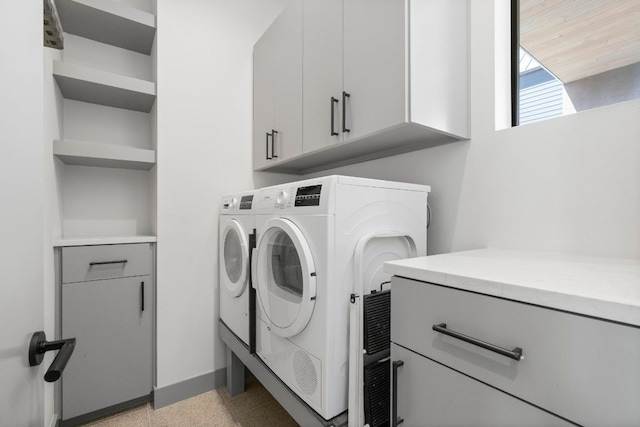 laundry room featuring baseboards, cabinet space, and washer and dryer