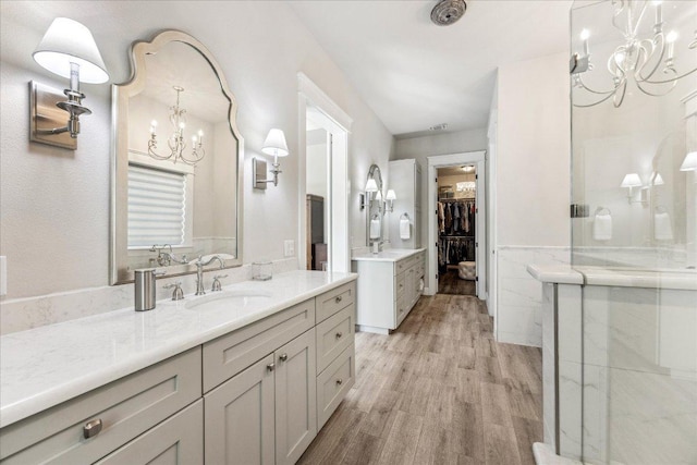 3204 Whitt Creek Trl, Leander, TX 78641 - bathroom with a chandelier, wood finished floors, a spacious closet, vanity, and a wainscoted wall