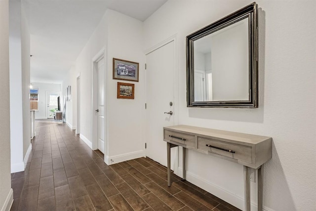 hallway featuring baseboards and dark wood finished floors