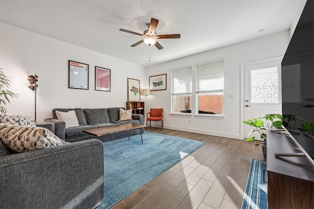living room featuring baseboards, a ceiling fan, and wood finish floors