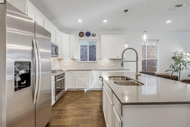 kitchen featuring tasteful backsplash, wood finish floors, visible vents, appliances with stainless steel finishes, and a sink