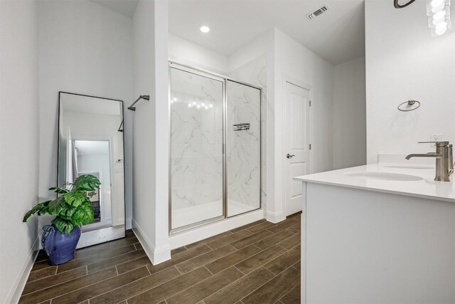 bathroom featuring wood finish floors, a marble finish shower, a sink, and visible vents