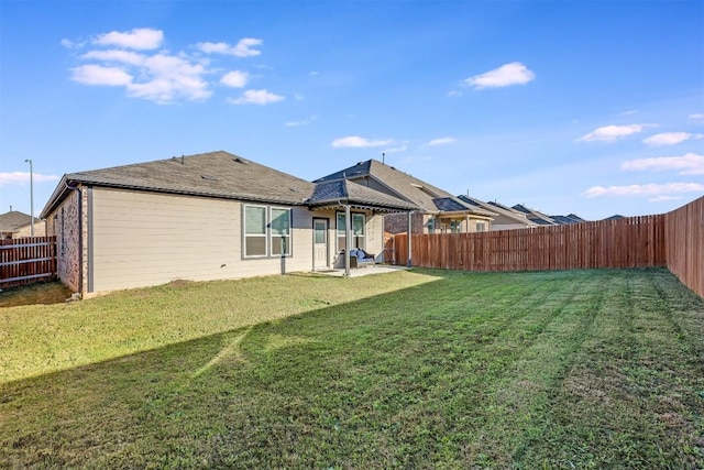 back of house featuring a yard, a patio, and a fenced backyard