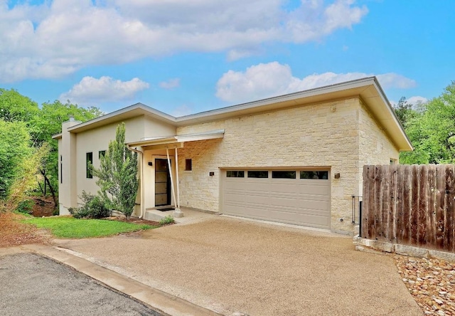 603 Westwood Ter, Austin, TX 78746 - view of front of property with an attached garage, stone siding, concrete driveway, and fence