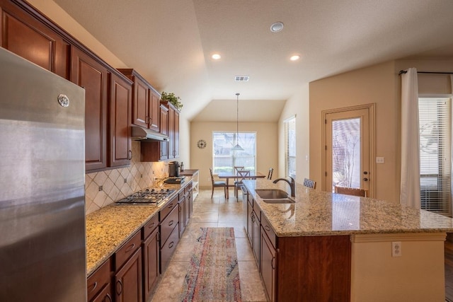 2705 Sixpence Ln, Pflugerville, TX 78660 - kitchen featuring stainless steel appliances, under cabinet range hood, a sink, decorative backsplash, and a kitchen island with sink