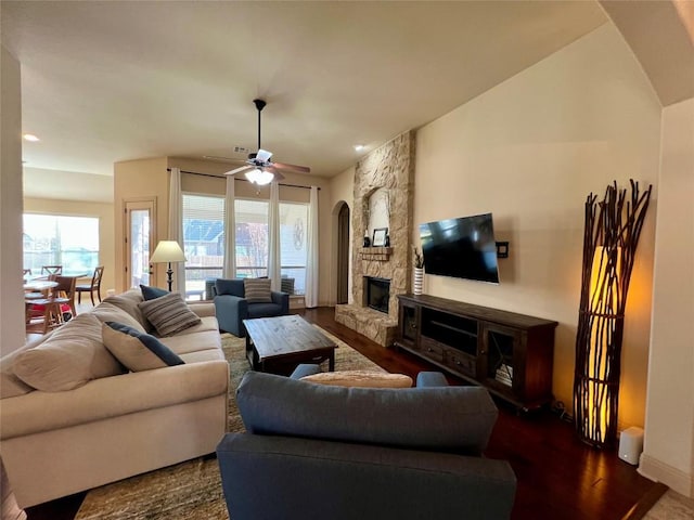 living room featuring a ceiling fan, baseboards, wood finished floors, and a fireplace