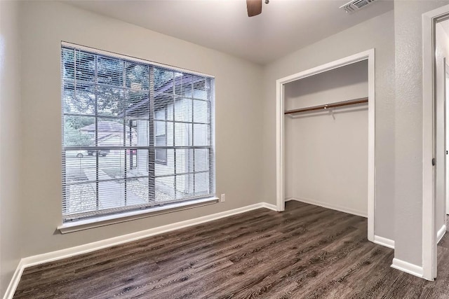 unfurnished bedroom with a closet, dark wood-style flooring, baseboards, visible vents, and a ceiling fan