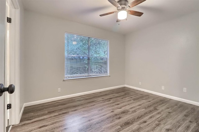 unfurnished room with a ceiling fan, baseboards, and dark wood finished floors
