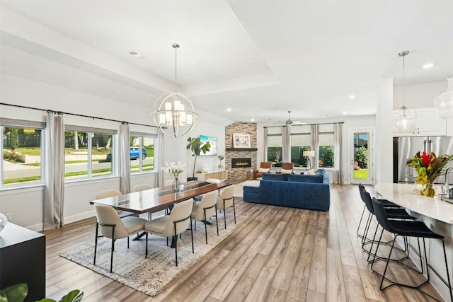 128 Mountain Lion Rd, Georgetown, TX 78628 - dining room with light wood-type flooring, a ceiling fan, a chandelier, recessed lighting, and a fireplace