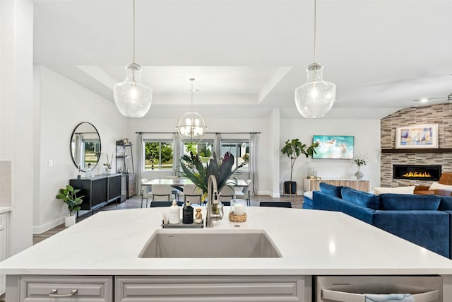 128 Mountain Lion Rd, Georgetown, TX 78628 - kitchen with open floor plan, light countertops, a fireplace, decorative light fixtures, and a tray ceiling