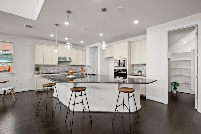 728 Pioneer Grv, Round Rock, TX 78665 - kitchen with under cabinet range hood, oven, dark countertops, dark wood finished floors, and recessed lighting