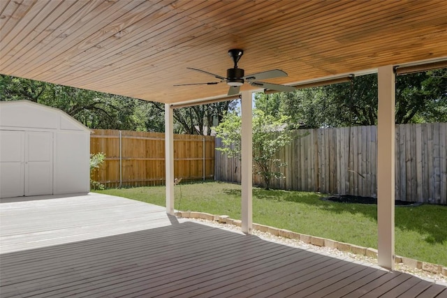 wooden terrace with a storage shed, a ceiling fan, and an outbuilding