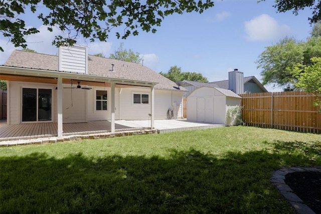 back of house featuring a shed, ceiling fan, an outdoor structure, a deck, and a shingled roof