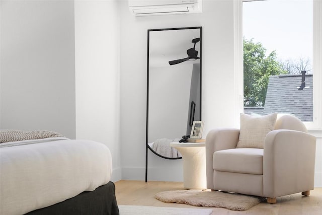 bedroom with a wall mounted AC and wood finished floors