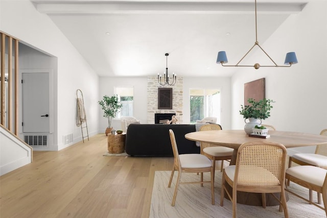 dining room featuring light wood-style flooring, a stone fireplace, and baseboards