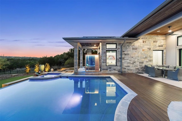 view of swimming pool featuring a wooden deck, an outdoor hangout area, a pool with connected hot tub, and fence