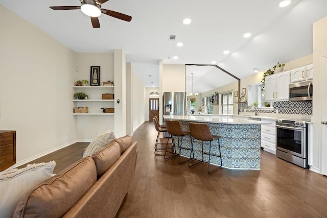 7306 Holly Fern Cv, Austin, TX 78750 - kitchen with appliances with stainless steel finishes, light countertops, white cabinetry, a breakfast bar, and dark wood-style flooring