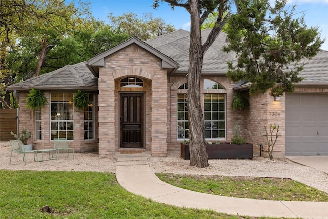 7306 Holly Fern Cv, Austin, TX 78750 - view of front facade featuring a shingled roof, a garage, a front yard, stone siding, and brick siding