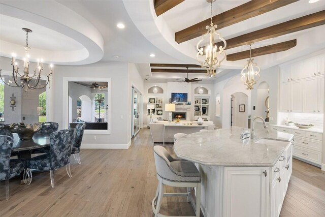 212 Bella Cima Dr, Austin, TX 78734 - kitchen with ceiling fan, a chandelier, a lit fireplace, arched walkways, and light wood-style flooring