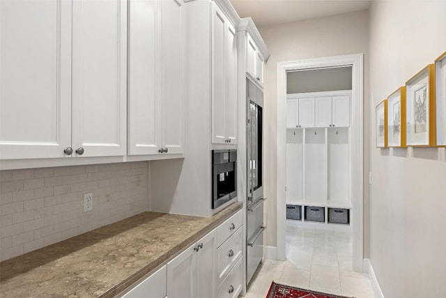 212 Bella Cima Dr, Austin, TX 78734 - kitchen with white cabinetry, backsplash, light stone counters, and light tile patterned floors