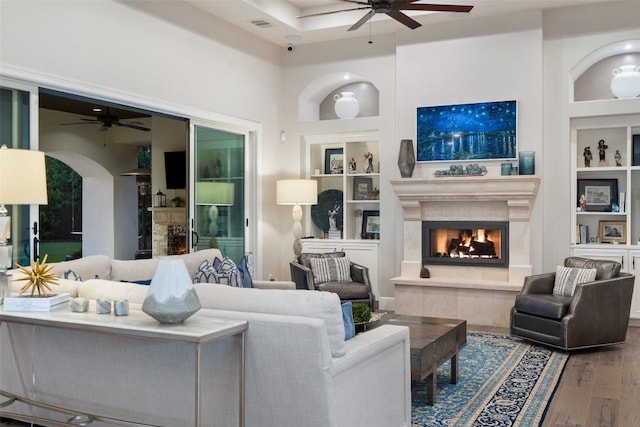 212 Bella Cima Dr, Austin, TX 78734 - living room featuring a ceiling fan, built in features, a lit fireplace, wood finished floors, and arched walkways