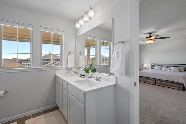 ensuite bathroom featuring a sink, plenty of natural light, and ceiling fan