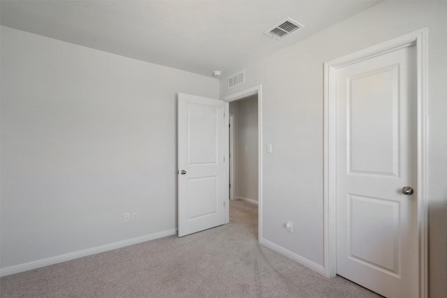 unfurnished bedroom with baseboards, light colored carpet, and visible vents
