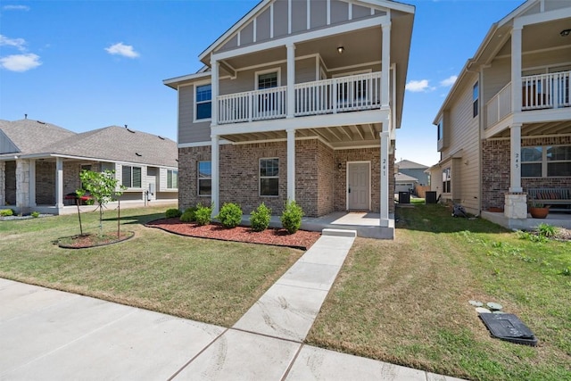 view of front of property featuring board and batten siding, brick siding, a balcony, and a front lawn
