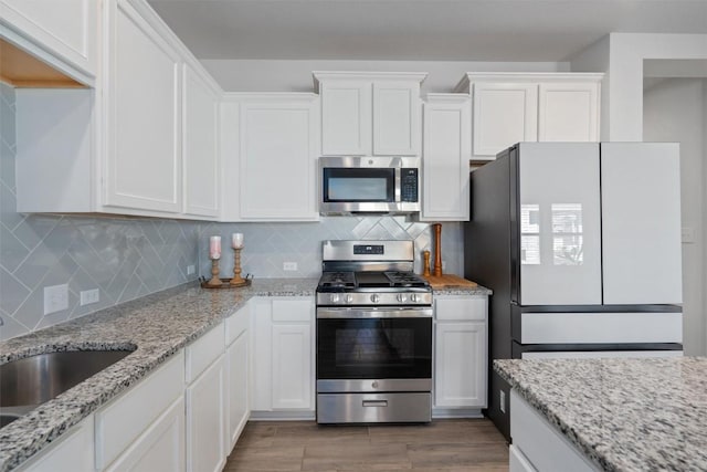 kitchen with white cabinets, appliances with stainless steel finishes, and decorative backsplash