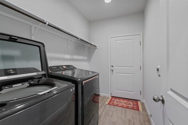 laundry area featuring laundry area, washing machine and dryer, baseboards, and wood tiled floor