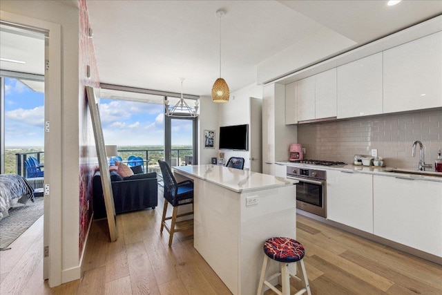 44 E Ave Unit 2509, Austin, TX 78701 - kitchen featuring stainless steel appliances, light wood-type flooring, a kitchen bar, tasteful backsplash, and white cabinetry